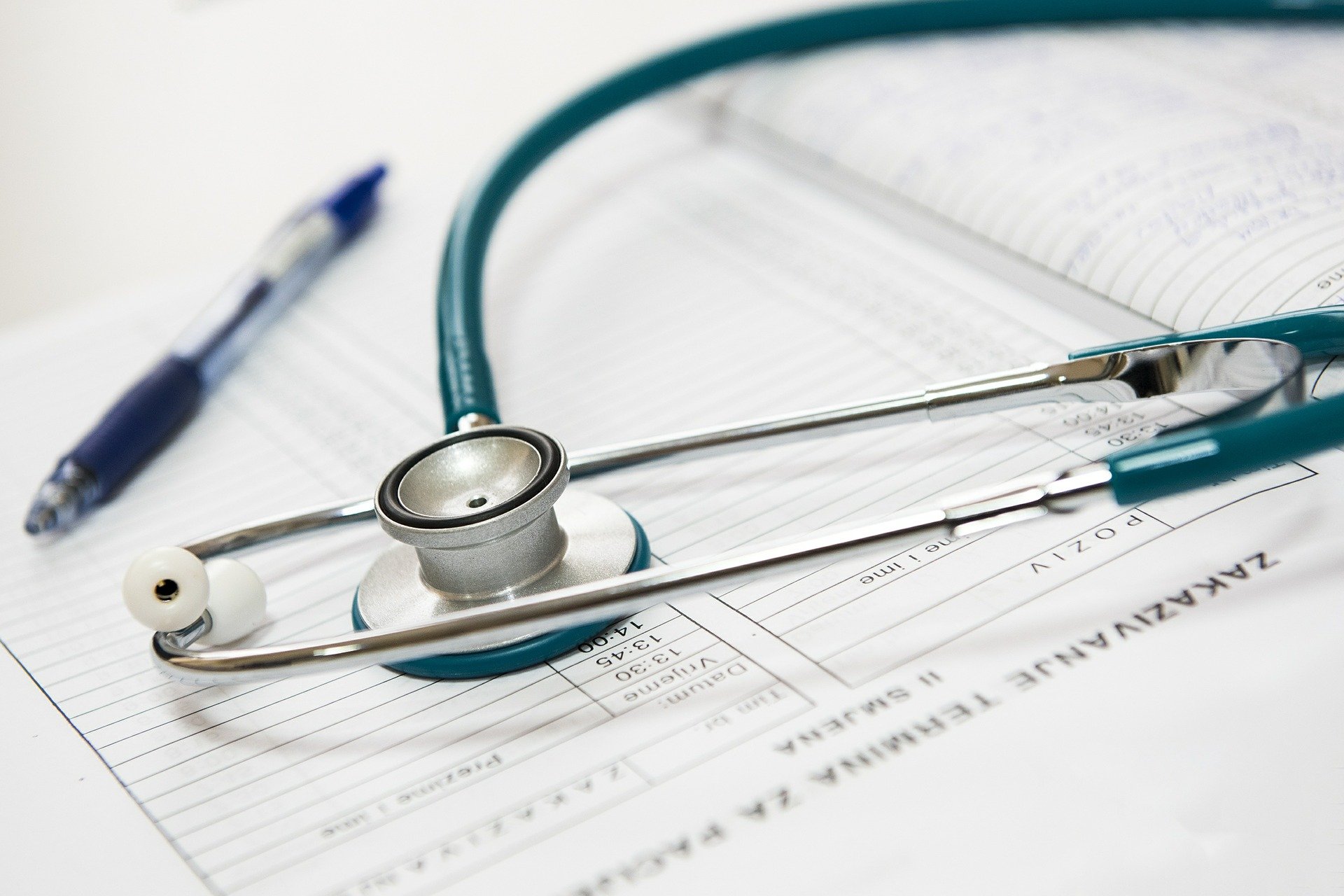 Medical stethoscope and blue ink pen laying on appointment booklet. HIPAA privacy notices.