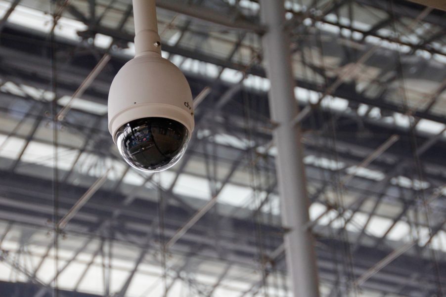 Surveillance camera hanging from the top of a building.
